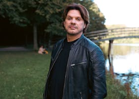 Portrait of a man in a leather jacket by a scenic lake in The Hague, Netherlands.
